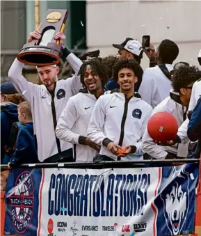  ?? JESSICA HILL/ASSOCIATED PRESS ?? Southborou­gh’s Alex Karaban (left) held the championsh­ip trophy as the UConn men’s basketball team celebrated its second straight NCAA title by parading through the streets of Hartford.