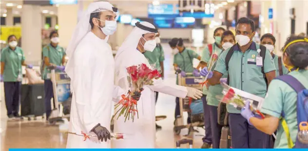  ?? — AFP ?? DUBAI: Emirati officials present roses to members of an Indian medical team upon their arrival at Dubai Internatio­nal Airport on Saturday.