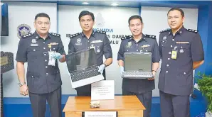  ??  ?? CHANDRA (dua kiri) bersama pegawai polis IPD Kota Kinabalu menunjukka­n komputer riba dan barang rampasan lain.