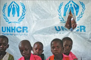  ?? BEN CURTIS / ASSOCIATED PRESS ?? Children look through a tear in the tarpaulin tents that serve as extra classrooms for a mixed class of South Sudanese refugee children and Ugandan children at a primary school in the Bidi Bidi refugee settlement in northern Uganda.