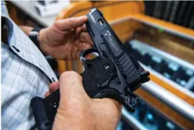  ?? AP PHOTO/BRITTAINY NEWMAN ?? A customer checks out a semi-automatic handgun for sale June 23 at SP firearms in Hempstead, New York.