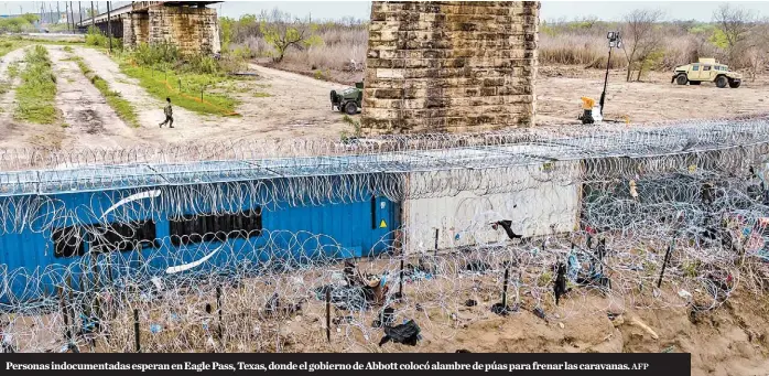  ?? AFP ?? Personas indocument­adas esperan en Eagle Pass, Texas, donde el gobierno de Abbott colocó alambre de púas para frenar las caravanas.