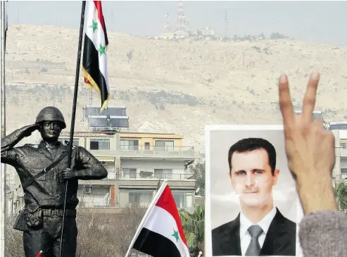  ?? LOUAI BESHARA / AFP / GETTY IMAGES FILES ?? Syrian regime supporters flash the victory sign and hold portraits of President Bashar al-Assad as they celebrate the unveiling of the Syrian Soldier statue at a rally in Damascus in 2011.