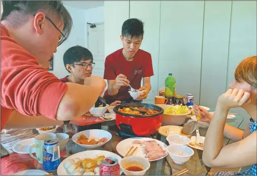  ?? (AP/Annabelle Liang) ?? Malaysian students Felix Mong, (from left), Ter Leong Kern and Siew Ee Sung enjoy a Lunar New Year hot pot lunch provided by their Malaysian host Chan Jit Yen (right) at her apartment in Singapore. With Malaysian workers and students stranded in the city-state over the Lunar New Year due to coronaviru­s travel restrictio­ns, the Malaysian Associatio­n in Singapore has called on Malaysians to treat students to a meal.