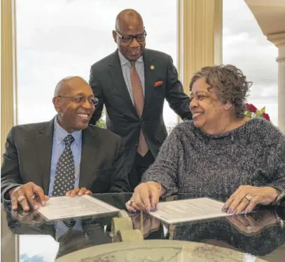  ?? PAUL “P.A.” GREENE/MORGAN STATE UNIVERSITY VIA AP ?? Calvin Tyler Jr. and his wife, Tina, smile after signing a giving pledge for $20 million to his alma mater, Morgan State University, as the university’s president, David K. Wilson, looks on at the Tylers’ home in Las Vegas on Feb. 20.
