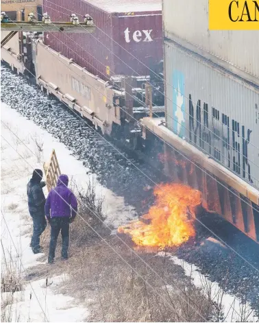  ?? ALEX FILIPE / REUTERS ?? A fire burns next to a passing CN Rail train Wednesday at an encampment in Tyendinaga Mohawk Territory, set up in support of B.C.’S Wet’suwet’en hereditary chiefs, who are trying to stop constructi­on of the Coastal Gaslink pipeline.
