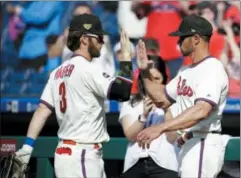  ?? MATT ROURKE — THE ASSOCIATED PRESS ?? Phillies right fielder Bryce Harper, left, and manager Gabe Kapler high-five after a win Sunday against the Colorado Rockies in Philadelph­ia.