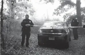  ?? Hot Springs Sentinel-Record ?? ■ Hot Springs Police Cpl. Kenny May sections off part of a crime scene Wednesday in the 2200 block of Lakeshore Drive where police say a Hot Springs woman killed her 8-year-old daughter and 71-year-old mother before trying to burn down the house.