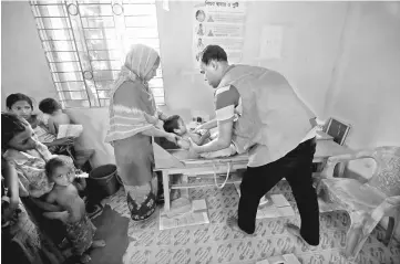  ?? — Reuters photo ?? A community health care assistant performs a health check-up on a Rohingya refugee child at Kutupalang Unregister­ed Refugee Camp, in Cox’s Bazar.