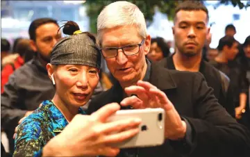  ??  ?? Apple CEO Tim Cook takes a selfie with a customer with her iPhone during a visit to the Apple Store in Chicago in March. — Reuters photo