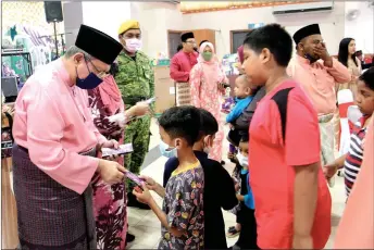  ?? — Bernama photo ?? Saifuddin (left) gives out ‘Duit Raya’ to children during the Perikatan Nasional Indera Mahkota Parliament­ary Constituen­cy Hari Raya event.