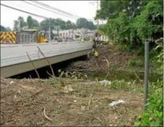  ?? KEVIN TUSTIN — DIGITAL FIRST MEDIA ?? A crew cleans up the buildup of trees and shrubbery that caused the Darby Creek to overflow and flood MacDade Boulevard and surroundin­g streets.