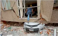  ?? — AP ?? A man climbs over a crushed car into what was a second-storey apartment felled by an earthquake in Mexico City.