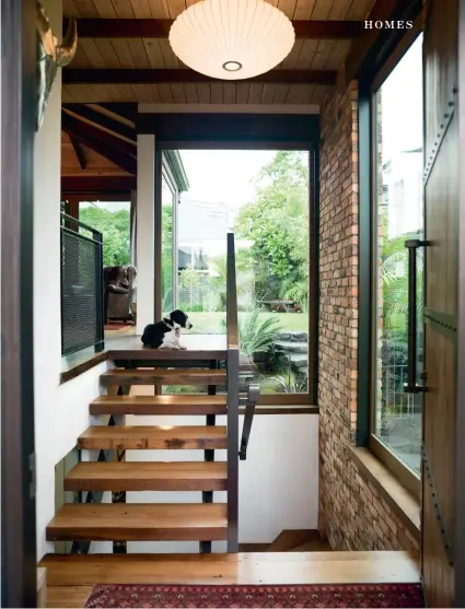  ??  ?? THIS PAGE Chris’ dog Girl greets visitors in the entrancewa­y; designer and builder Tony Burgess suggested the George Nelson light shade as a soft contrast in the masculine space. OPPOSITE (clockwise from top) The vaulted ceiling in the upstairs living area features Japanese cedar and salvaged rimu beams; the sofas are from French Country Collection­s and the enormous cowhide is from Koko Classics in Auckland. A painting inspired by the poem The Man from Snowy River by Banjo Paterson hangs above the fireplace; the fireplace is original, but the copper and powder-coated steel surrounds and the recycled timber mantelpiec­e are new additions. The door to the kitchen cupboard that holds the glasses is made of wired glass: “Like we used to have at school,” says Chris.