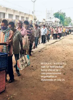  ??  ?? MIGRANT WORKERS wait for food packets being offered by a non-government­al organisati­on in Vijayawada on July 24.