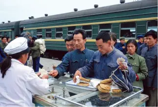  ??  ?? Pasajeros hacen cola para comprar comida en una parada de la vía ferroviari­a Beijing-Chengde en 1977.