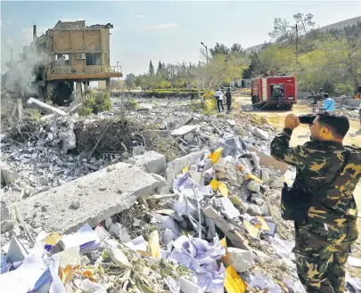  ??  ?? Syrische Soldaten hielten am Wochenende nach den Luftschläg­en der USA, Frankreich­s und Großbritan­niens die Schäden an militärisc­hen Forschungs­einrichtun­gen fest.