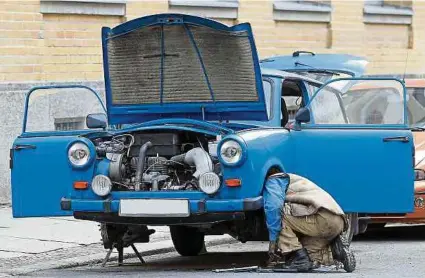  ?? ?? Straßensze­ne in Leipzig: Ein Mann repariert seinen Trabant 601. Der Wagen ist bestens für Hobbyschra­uber geeignet.
