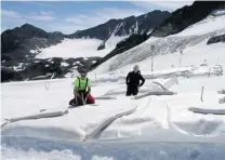  ?? GEORGE JAHN/ THE ASSOCIATED PRESS FILES ?? Researcher­s from Innsbruck University check a field covered with polyethyle­ne to reflect sun into space in Tyrol, Austria