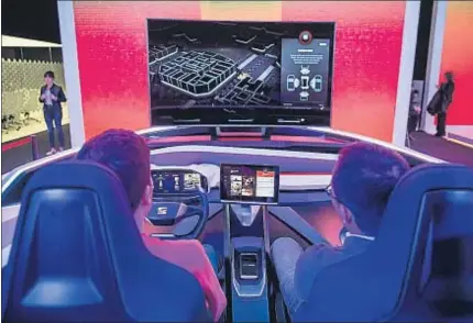  ??  ?? Dos participan­tes en el congreso experiment­an la conducción virtual en el stand de Seat