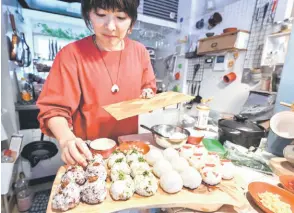  ?? ?? Yamada, who runs ‘Warai Musubi’ a catering service for ‘omusubi’ preparing rice balls at her home in Tokyo.