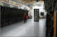  ?? THE ASSOCIATED PRESS ?? A worker walks along a row of computer rigs that run around the clock “mining” bitcoin inside the Genesis Mining cryptocurr­ency mine in Keflavik, Iceland.