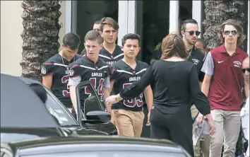  ?? Joel Auerbach/Associated Press ?? Members of the Marjory Stoneman Douglas High School football team depart the service at the Church by the Glades in Coral Springs, Fla., on Thursday for Aaron Feis, the football coach who was killed during the school shooting last week.