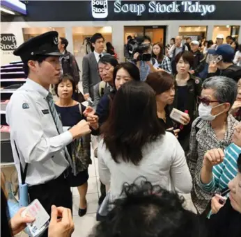  ?? AKIKO MATSUSHITA/THE ASSOCIATED PRESS ?? A station attendant responds to passengers in Tokyo after a blackout on suspended rush-hour train services.