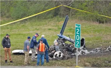  ?? AP PHOTO/GEORGE WALKER IV ?? Investigat­ors look over the wreckage of a small plane that crashed Tuesday alongside eastbound Interstate 40 in Nashville.