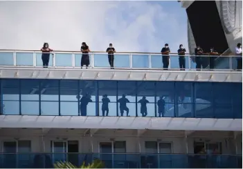  ??  ?? Passengers look out from the deck on cruise ship Coral Princess as it docks at the Port of Miami after receiving permission from the US Coast Guard.