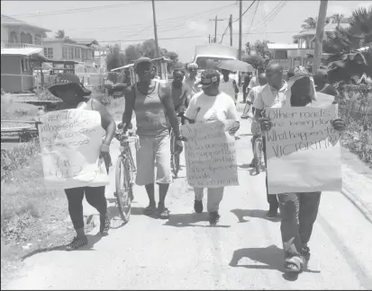  ??  ?? Residents of Victoria, East Coast Demerara, armed with placards walking along Middle Walk Road which they say needs immediate repairs (Dhanash Ramroop photo)