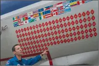  ?? (AP/Gemunu Amarasingh­e) ?? Lt. Commander Sam Urato, a P-3 pilot of National Oceanic and Atmospheri­c Administra­tion, points to decals on the fuselage of the “hurricane hunter” aircraft representi­ng the hurricanes it has entered during a hurricane awareness tour.