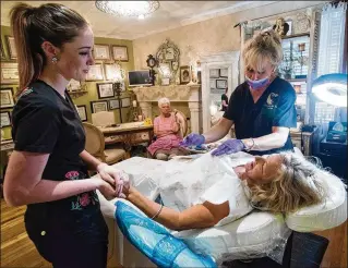  ?? TONY GIBERSON / PENSACOLA NEWS JOURNAL ?? Laura Lee Williams (left) soothes Bobbie Jean Joiner as permanent makeup specialist Trinkette Parker applies a medical tattoo recently in Pensacola to restore the look of an areola.