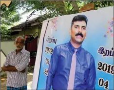  ??  ?? Velusami Raju, father of the Zion Church suicide blast victim Ramesh Raju, looks on next to a banner displaying Raju Ramesh’s portrait at his house, in Kattankudy. — AFP photo