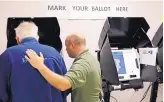  ?? DAVID GOLDMAN/ASSOCIATED PRESS ?? In this October 2017 photo, James Cabe, right, helps Ed Messer as they vote using new machines at a polling site in Conyers, Ga. Last summer, a security expert found a gaping hole in Georgia’s election management system. The revelation prompted a...