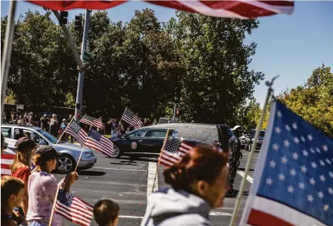  ?? Stephen Lam / The Chronicle ?? People wave American flags as the procession carrying the casket of Marine Sgt. Nicole Gee drives away from Bayside Church.