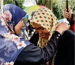  ?? PIC BY MIKAIL ONG ?? Siti Hajar Ghazali (right) being consoled after the burial of her son, Muhammad Saifullah Muhammad Hafiez, at the Bayan Lepas Muslim cemetery in George Town yesterday.