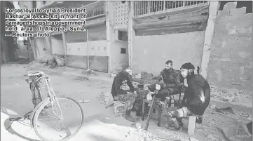  ??  ?? Forces loyal to Syria’s President Bashar al-Assad sit in front of damaged shops in a government held area of Aleppo, Syria. — Reuters photo