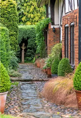  ??  ?? A classical bust provides a focal point at the far end of a stone path alongside the farmhouse.