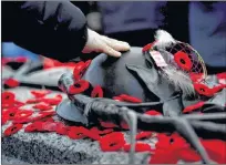  ?? CP PHOTO ?? A man touches the helmet on the Tomb of the Unknown Soldier after laying a poppy following the National Remembranc­e Day Ceremony at the National War Memorial in Ottawa on Saturday, Nov. 11, 2017. A new survey suggests Canadians of all generation­s are more likely to honour military veterans by attending a Remembranc­e Day ceremony this year.