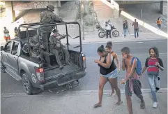  ?? AFP ?? Locals walk past a truck carrying militarise­d police members during an operation at the Salgueiro Complex, in Sao Goncalo, Rio de Janeiro state on Thursday.