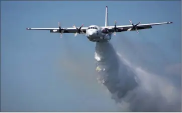  ?? RFS VIA AP ?? A C-130 Hercules airplane drops water during a flight in Australia in this undated photo from the New South Wales Rural Fire Service. A similar C-130 firefighti­ng air tanker crashed Thursday while battling wildfires in southeaste­rn Australia, killing three American crew members, officials reported.