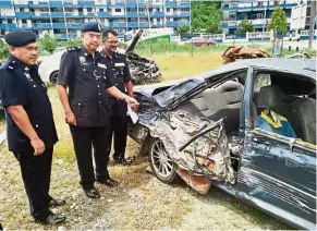  ??  ?? Badly damaged: Supt Som Sak (second from left) showing the Proton Iswara that was also involved in Saturday’s accident.