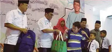  ?? PIC BY HAIRUL ANUAR RAHIM ?? Johor Menteri Besar Datuk Seri Mohamed Khaled Nordin
(second from left) handing over school aid to recipients in Bandar Permas Jaya, Johor Baru, on
Friday. With them is Johor Islamic Religious Council chief executive officer Abdul Alim Shukor (left).