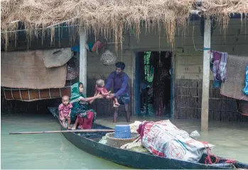  ?? GETTY-AFP ?? A woman reaches for a child as they evacuate their flooded house Sunday in Goyainghat, Bangladesh. Flooding from swollen rivers in Bangladesh and neighborin­g India have left millions displaced. In India’s northeaste­rn Assam state, officials said 32 of the 35 districts were underwater after the Brahamaput­ra River overflowed its banks.