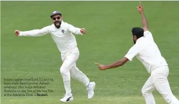  ?? — Reuters ?? India’s captain Virat Kohli (L) and his team-mate Ravichandr­an Ashwin celebrate after India defeated Australia on day five of the first Test at the Adelaide Oval.
