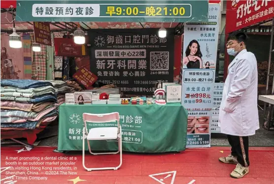  ?? — ©2024 The new york Times Company ?? a man promoting a dental clinic at a booth in an outdoor market popular with visiting Hong Kong residents, in shenzhen, China.