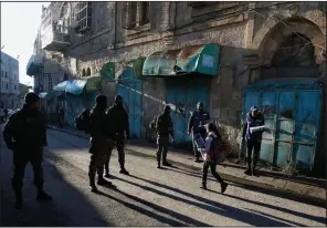  ?? AP/MAJDI MOHAMMED ?? Palestinia­n observers (right) keep an eye on children walking past Israeli soldiers Tuesday on their way to school in the West Bank city of Hebron. Palestinia­n activists are handling patrols to document alleged Israeli settler violence.