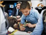  ?? ERIC ALBRECHT — THE COLUMBUS DISPATCH VIA AP ?? Third grade student Evan Seifert having Jax a therapy dog nuzzle into his religious lesson at St. Francis de Sales School in Newark.