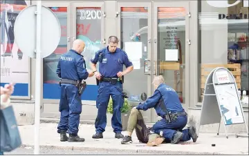  ?? — Reuters photo ?? The suspect lies on the ground surrounded by police officers at the Market Square where several people were stabbed, in Turku, Finland.
